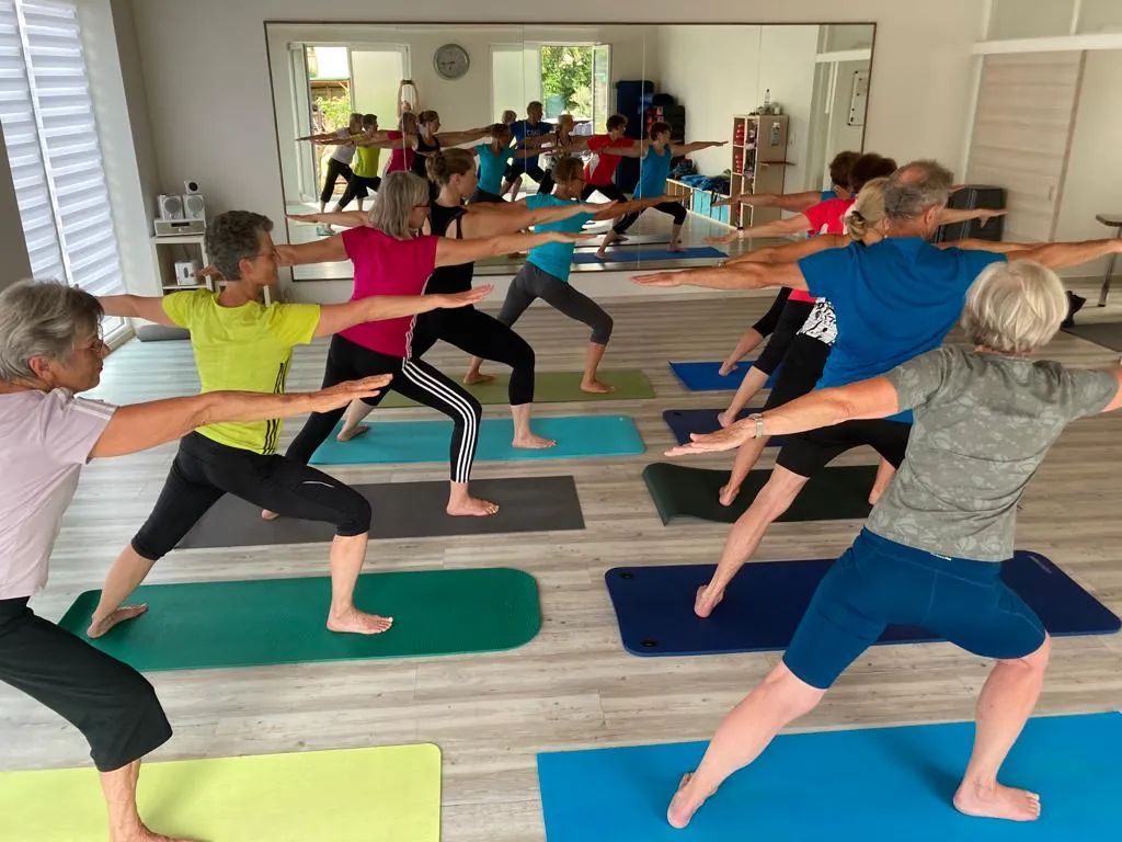 Gymnastikgruppe bei einer Yoga-Übung im Gymnastikraum